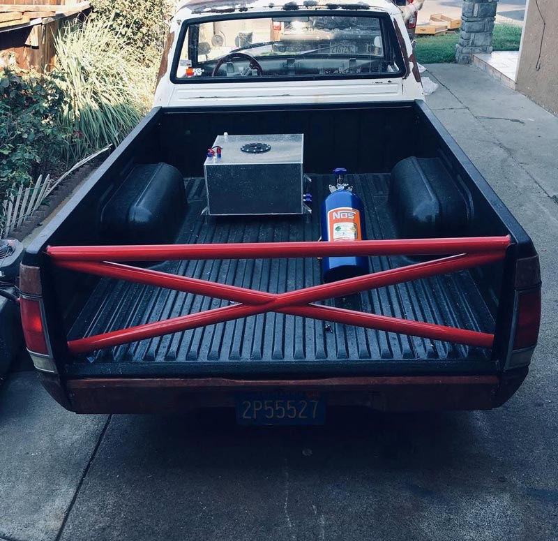 Truck bed showing NOS nitrous bottle and custom roll cage setup