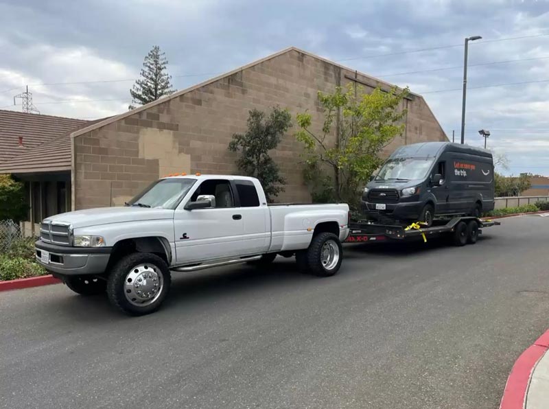 Dodge Ram towing truck with van loaded on flatbed trailer